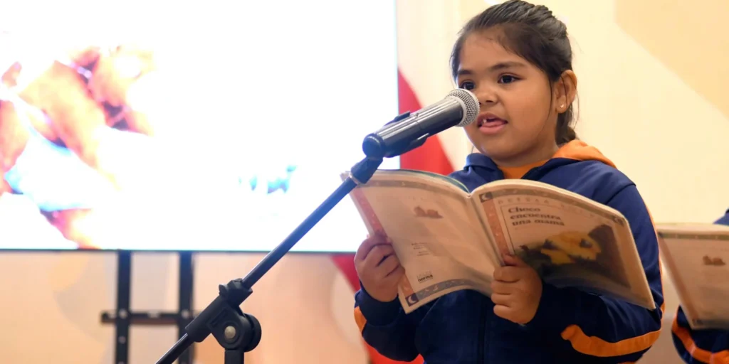 Primer plano de una niña chilena concentrada leyendo un texto en el podio durante la ceremonia de lanzamiento de la Red por un Chile que Lee.