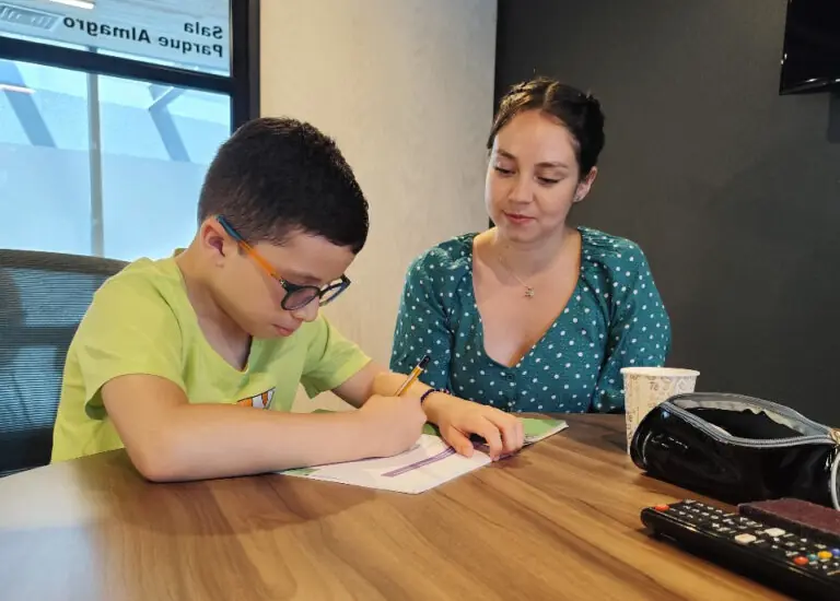 Profesora ayudando a un niño a resolver una duda sobre un texto escolar.