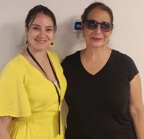 Profesora y alumna interactuando de forma alegre mientras revisan materiales didácticos.