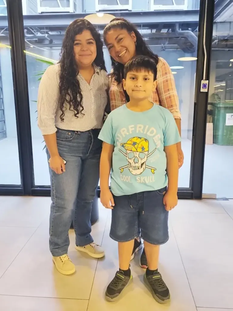 Dos profesoras y un alumno joven posando juntos de forma amigable en un salón moderno de Alfabeta.