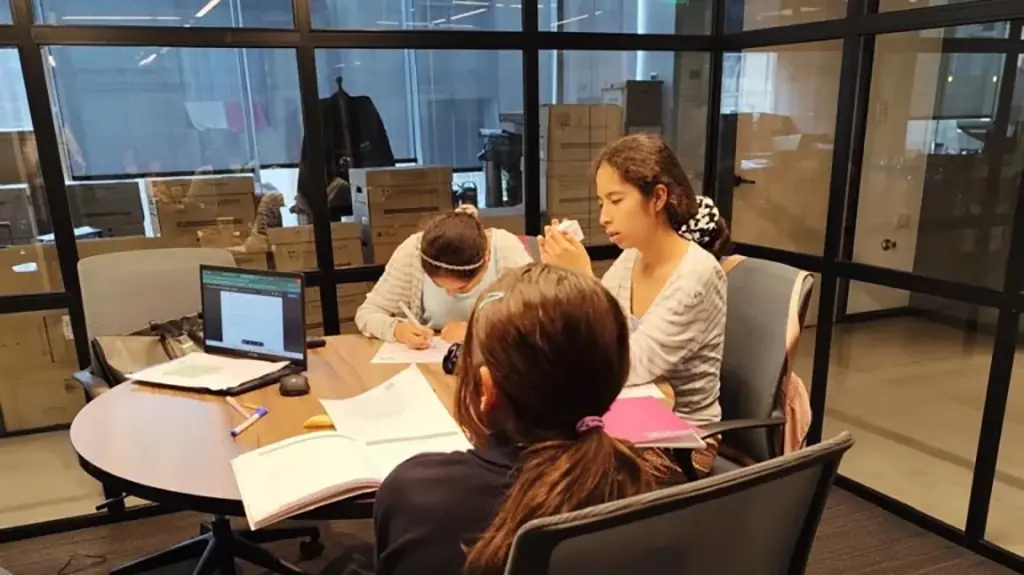 Niñas ojeando con entusiasmo una enciclopedia o libro informativo, como si descubrieran un dato sorprendente juntas.