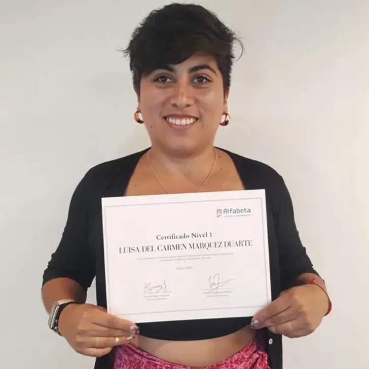 Alumna posando con su certificación recién entregada en el salón principal.